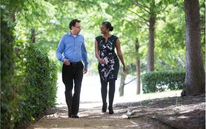 Man and woman strolling and chatting along wooded walkway