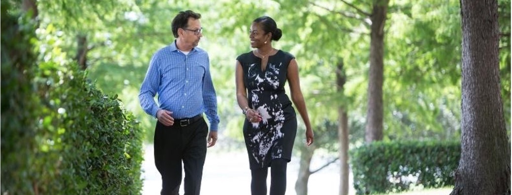 Man and woman strolling and chatting along wooded walkway