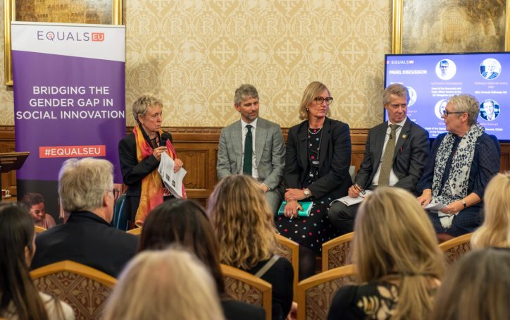 Five panelists discuss gender gap in social innovation at an event, with an audience seated in front of them.